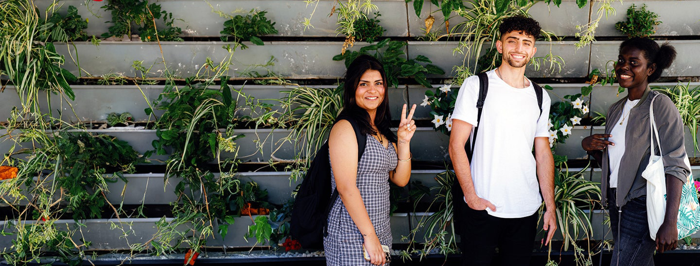 Happy students standing front of garden wall