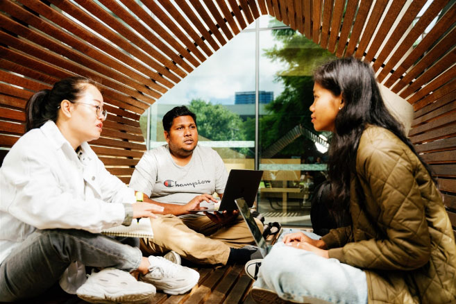 Students on campus sitting smiling